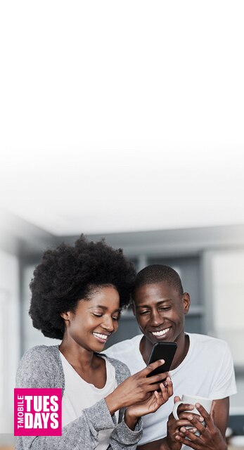 Two people smiling and looking at a phone together.