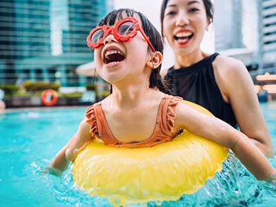 Child in an inner tube in a hotel pool with an adult behind them.
