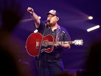 Luke Combs on stage with a guitar.